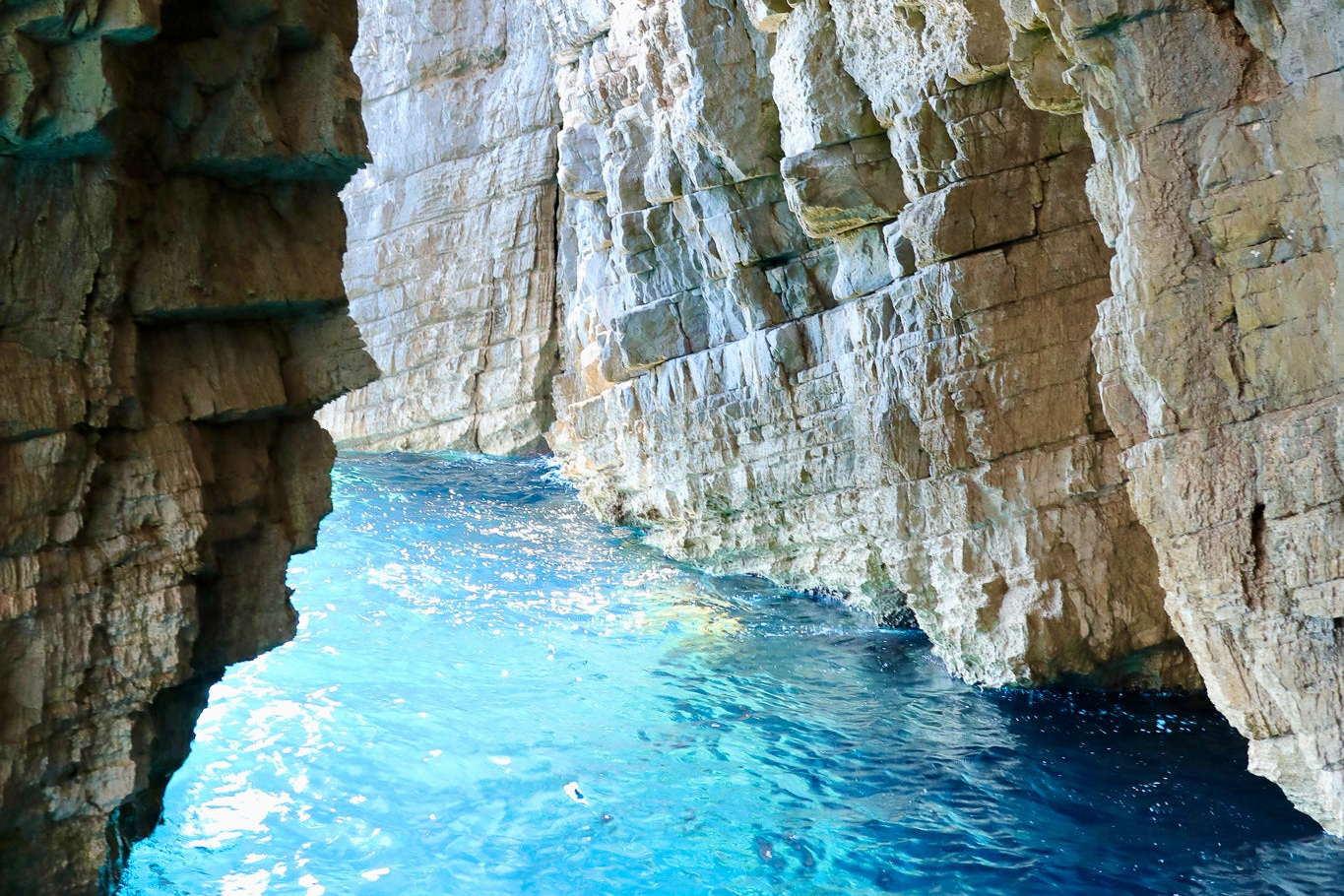 Cave entrance with clear blue water and rocky walls